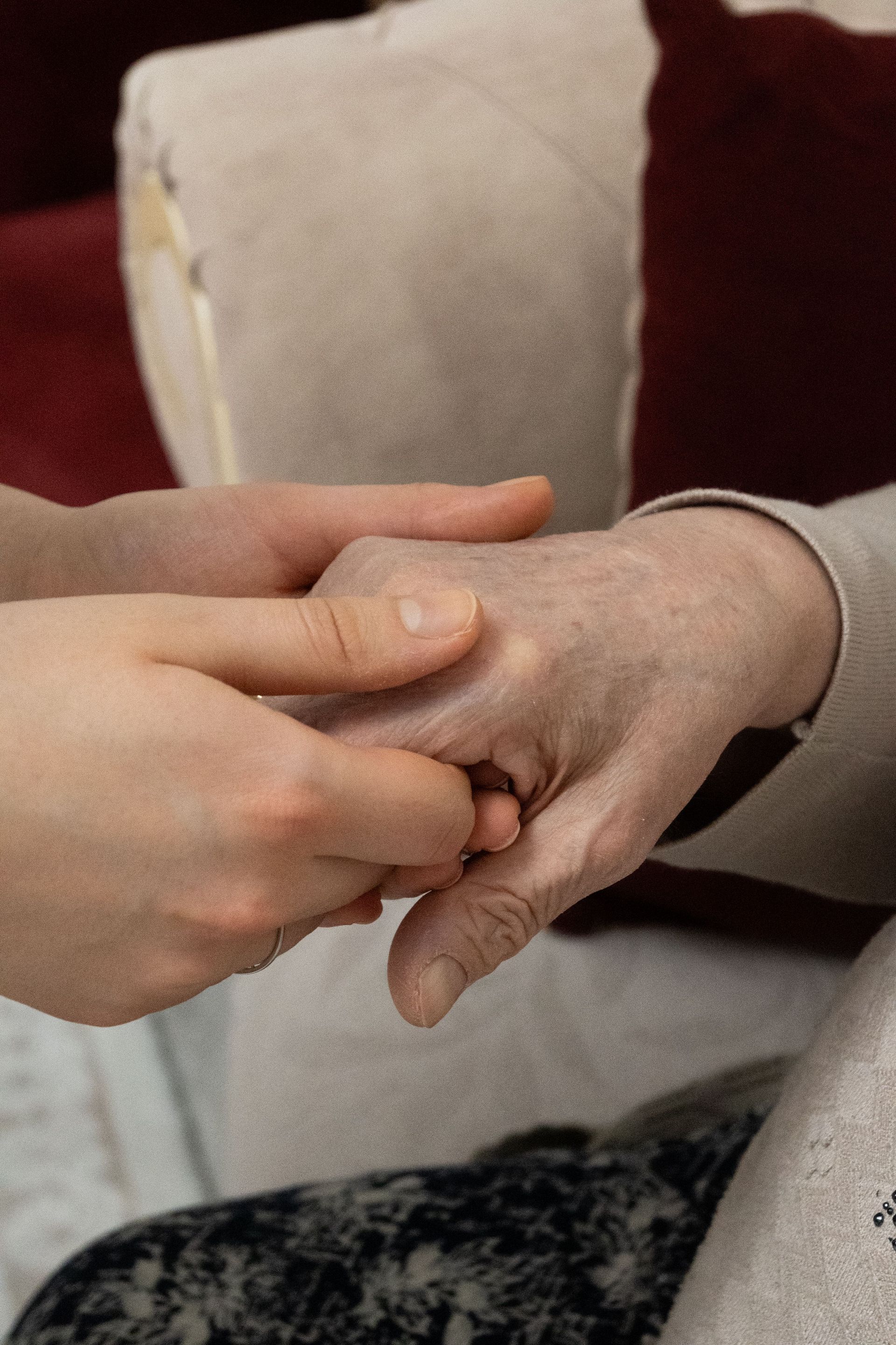 A younger person holds a senior adult's hand, symbolizing care and support.